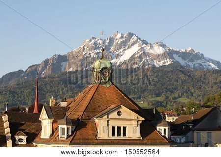LUCERNE SWITZERLAND - MAY 06 2016: Sloping roof covered with tiles of a historic building shows a proximity of the city to the snowy peak of Pilatus one of the most well-known peaks in Switzerland