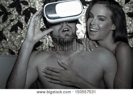 Young excited man in VR glasses with girlfriend foreplay at night