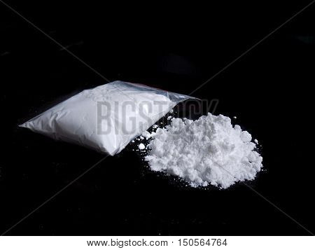 Cocaine drug powder in bag and cocaine powder pile on black background