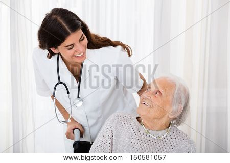 Caring Female Doctor Helping Handicapped Senior Patient In Hospital