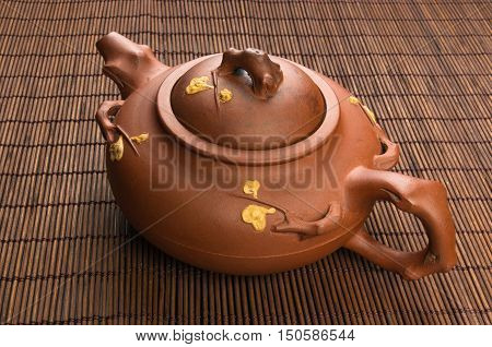 brown Chinese teapot of Yixing clay with traditional ornament on bamboo Mat
