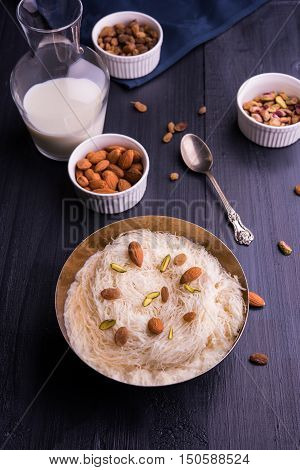Indian sweet sutarfeni or sutar feni or firni or seviyan or laccha, shredded, flaky-rice-flour roasted in ghee, blended with melted sugar to form a cotton candy, topped with pistachio and almonds