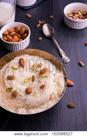 Indian sweet sutarfeni or sutar feni or firni or seviyan or laccha, shredded, flaky-rice-flour roasted in ghee, blended with melted sugar to form a cotton candy, topped with pistachio and almonds