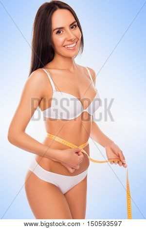 Portrait Of Beautiful Fit Slim Woman In White Lingerie Measuring Her Waist