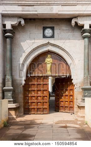 Madurai India - October 21 2013: The relatively small main entrance to the Nayak Palace features a double wooden door with a golden statue on top.