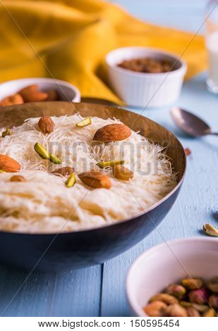 Indian sweet sutarfeni or sutar feni or firni or seviyan or laccha, shredded, flaky-rice-flour roasted in ghee, blended with melted sugar to form a cotton candy, topped with pistachio and almonds