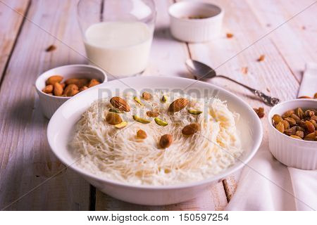 Indian sweet sutarfeni or sutar feni or firni or seviyan or laccha, shredded, flaky-rice-flour roasted in ghee, blended with melted sugar to form a cotton candy, topped with pistachio and almonds