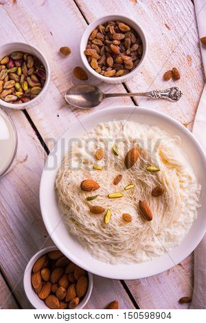 Indian sweet sutarfeni or sutar feni or firni or seviyan or laccha, shredded, flaky-rice-flour roasted in ghee, blended with melted sugar to form a cotton candy, topped with pistachio and almonds
