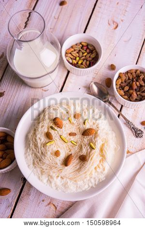 Indian sweet sutarfeni or sutar feni or firni or seviyan or laccha, shredded, flaky-rice-flour roasted in ghee, blended with melted sugar to form a cotton candy, topped with pistachio and almonds