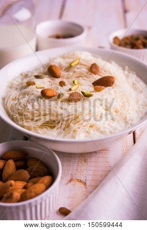 Indian sweet sutarfeni or sutar feni or firni or seviyan or laccha, shredded, flaky-rice-flour roasted in ghee, blended with melted sugar to form a cotton candy, topped with pistachio and almonds