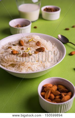 Indian sweet sutarfeni or sutar feni or firni or seviyan or laccha, shredded, flaky-rice-flour roasted in ghee, blended with melted sugar to form a cotton candy, topped with pistachio and almonds