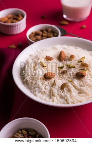 Indian sweet sutarfeni or sutar feni or firni or seviyan or laccha, shredded, flaky-rice-flour roasted in ghee, blended with melted sugar to form a cotton candy, topped with pistachio and almonds