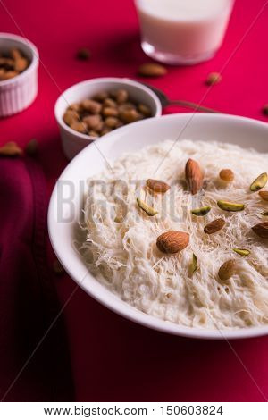 Indian sweet sutarfeni or sutar feni or firni or seviyan or laccha, shredded, flaky-rice-flour roasted in ghee, blended with melted sugar to form a cotton candy, topped with pistachio and almonds