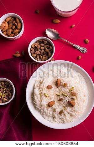 Indian sweet sutarfeni or sutar feni or firni or seviyan or laccha, shredded, flaky-rice-flour roasted in ghee, blended with melted sugar to form a cotton candy, topped with pistachio and almonds