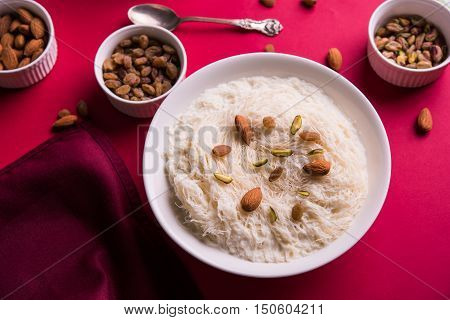 Indian sweet sutarfeni or sutar feni or firni or seviyan or laccha, shredded, flaky-rice-flour roasted in ghee, blended with melted sugar to form a cotton candy, topped with pistachio and almonds