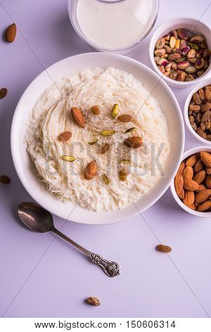Indian sweet sutarfeni or sutar feni or firni or seviyan or laccha, shredded, flaky-rice-flour roasted in ghee, blended with melted sugar to form a cotton candy, topped with pistachio and almonds