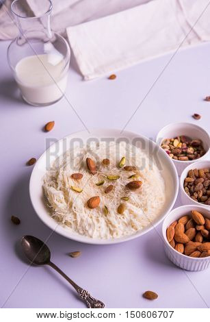 Indian sweet sutarfeni or sutar feni or firni or seviyan or laccha, shredded, flaky-rice-flour roasted in ghee, blended with melted sugar to form a cotton candy, topped with pistachio and almonds