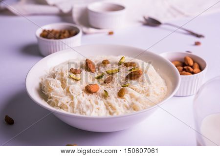 Indian sweet sutarfeni or sutar feni or firni or seviyan or laccha, shredded, flaky-rice-flour roasted in ghee, blended with melted sugar to form a cotton candy, topped with pistachio and almonds