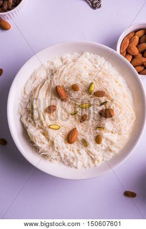 Indian sweet sutarfeni or sutar feni or firni or seviyan or laccha, shredded, flaky-rice-flour roasted in ghee, blended with melted sugar to form a cotton candy, topped with pistachio and almonds
