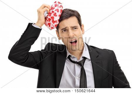Young businessman having a headache and holding an icepack isolated on white background