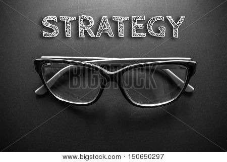 Text strategy with eyeglasses on black background / business concept / dark tone