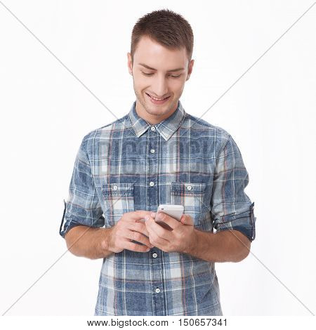 Young man using smart phone standing against white background. Happy young man. Portrait of handsome Man in casual shirt and smiling while standing against at white wall