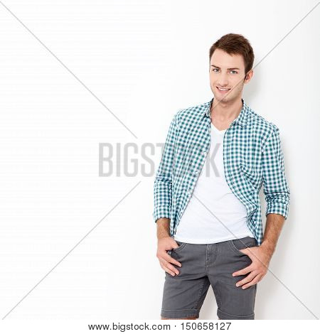 Happy young man. Portrait of handsome young man in casual shirt keeping arms crossed and smiling while standing against white background