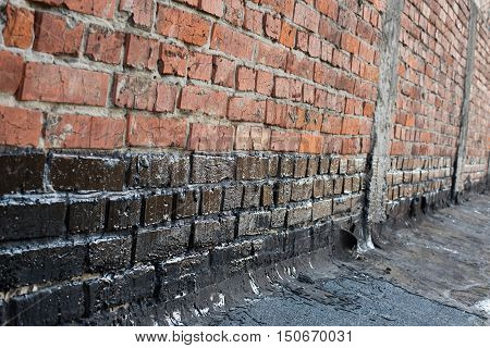 Covered brick wall bitumen primer for improving adhesion during surfacing contiguity with rolled waterproofing during the installation of flat roof.