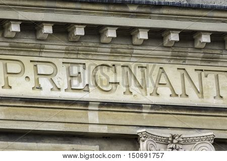 The word pregnant isolated from a much larger latin inscription carved in stone.
