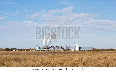 Smoke billowing out of smoke stacks at an industrial agriculture processing plant in autumn landscape