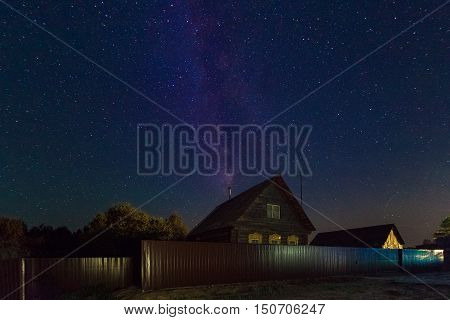 The Milky Way. A beautiful August summer night sky with stars on the background of a village house. Starfall the falling Perseids.