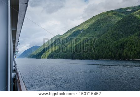 Cruise ship sails past virgin green forests of the Inside Passage off the coast of British Columbia.