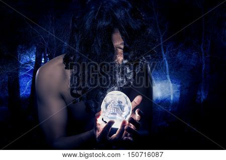Primitive looking man in a dark smoky forest as a witch doctor or shaman