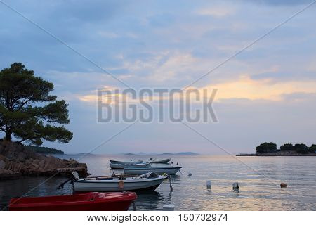 Colorful motor boats at anchor in calm blue sea water inshore after sunset on beautiful evening seascape