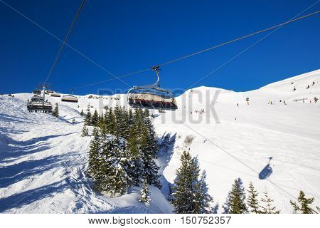 KITZBUEHEL AUSTRIA February 18 2016 - Skiers on ski lift enjoying the view to foggy Alps in Austria and beautiful snowy country panorama in famous Kitzbuehel mountain ski resort