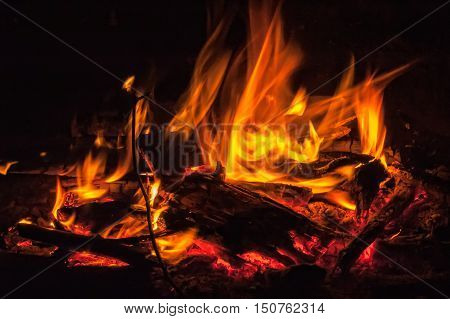The red flames of gas burning over black background.