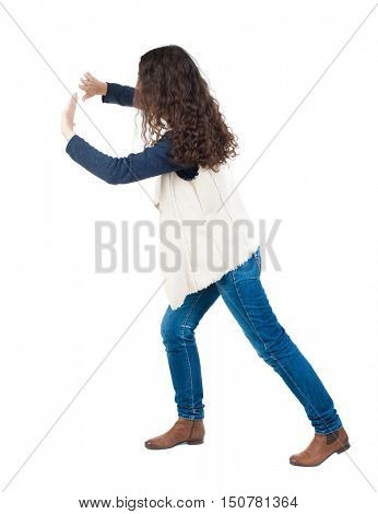 back view of woman pushes wall. Isolated over white background. Rear view people collection. backside view of person. curly girl put her hands on the obstacle. A girl in a white tank top is pushing