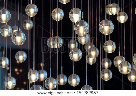 lighting balls on the chandelier in the lamplight light bulbs hanging from the ceiling lamps on the dark background selective focus horizontal