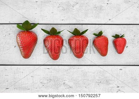 Strawberries lying on white table in row order. Line of strawberry on the white wooden table. 3D illustration