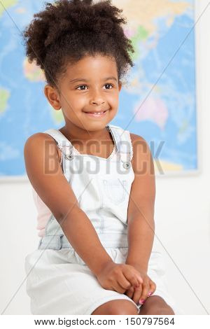 Cute preschool girl with world map at the class room