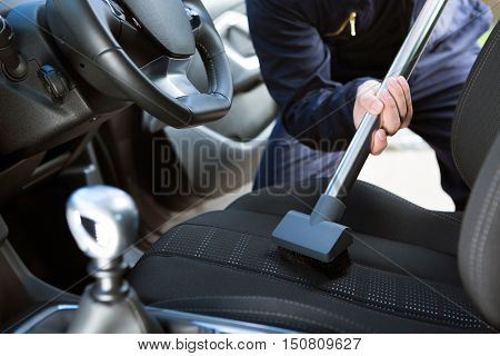 Man Hoovering Seat Of Car During Car Cleaning