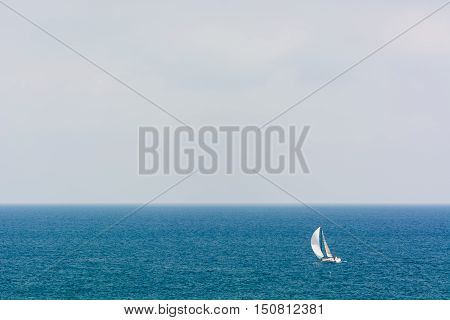 A sailboat sailing by sea on a foggy day.