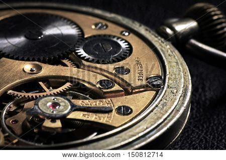 Pocket watch inside with wheels and springs close up on dark background