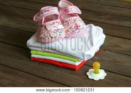 Kit for newborns. Baby clothes, booties on wooden background .