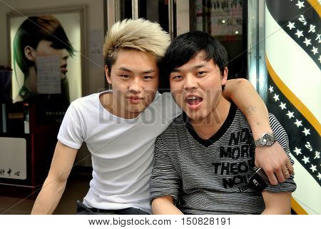 Pengzhou China - April 17 2011: Two Chinese hair stylists with trendy haircuts sitting in front of their salon