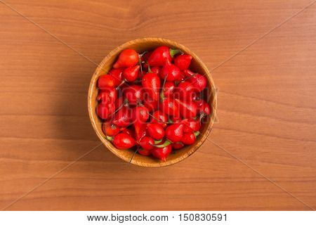 Biquinho Pepper into a bowl. Capsicum Chinense over a wooden table