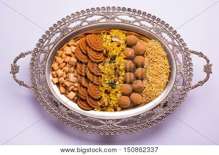Plate full of indian festival food or diwali food or snacks like laddu, chivda, chakali or murukku, sev and shankar pale, sweet and salty snack food