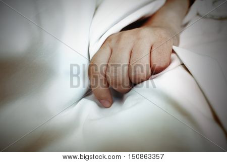 Hand on the white sheet as a concept a metaphor of disease indisposition.
