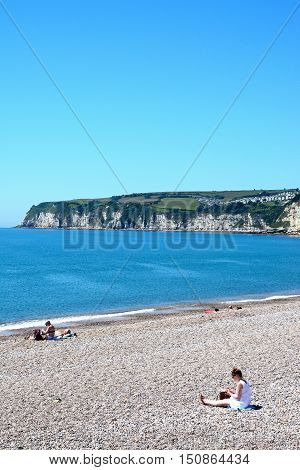 SEATON, UNITED KINGDOM - JULY 18, 2016 - View of the pebble beach and coastline with holidaymakers enjoying the setting Seaton Devon England UK Western Europe, July 18, 2016.