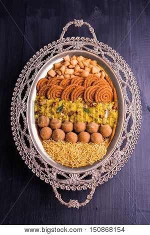 Plate full of indian festival food or diwali food or snacks like laddu, chivda, chakali or murukku, sev and shankar pale, sweet and salty snack food